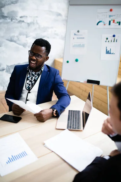 Empresario africano en una chaqueta azul con una pizarra blanca en el fondo presenta un nuevo proyecto para aumentar las ventas . — Foto de Stock