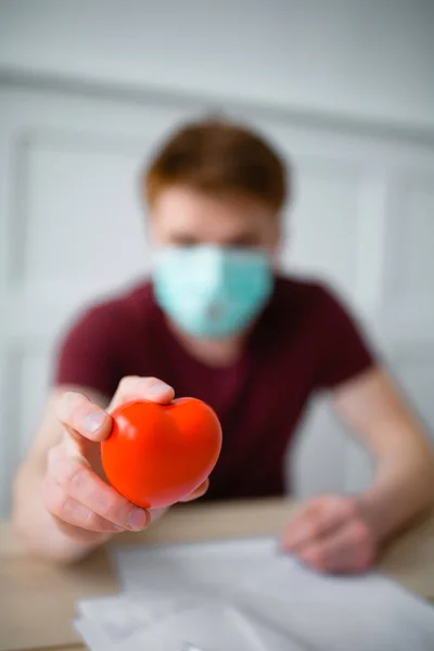 Закрыть фотографию рыжеволосого кардиолога с красным игрушечным сердцем. Ориентировочное фото рук врачей — стоковое фото