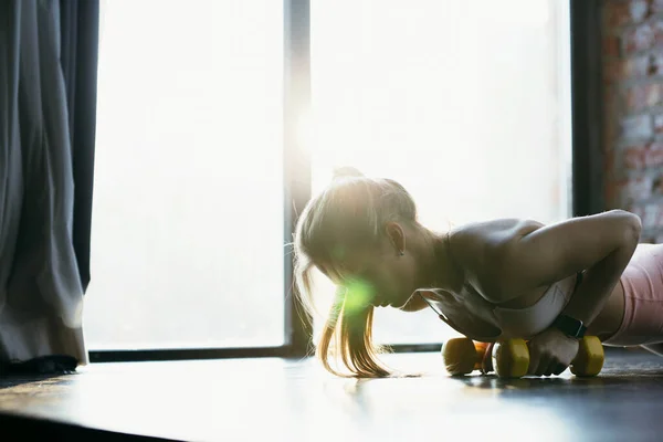 Close-up dari pelatihan gadis dengan dumbel kuning di gym. Latihan dalam spotswear dekat jendela . — Stok Foto
