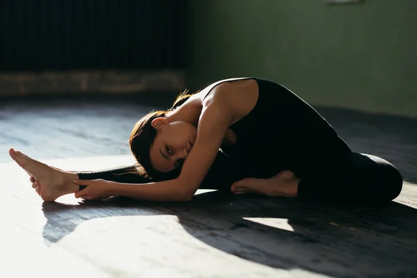 O fată tânără face exerciții de întindere. Clasa de yoga în îmbrăcăminte sport neagră de zi însorită . — Fotografie, imagine de stoc
