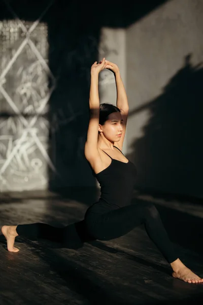 Frumoasa fata face yoga exercițiu lunge în sala de gimnastică. Cursuri de yoga de dimineață în îmbrăcăminte sport neagră de zi însorită . — Fotografie, imagine de stoc