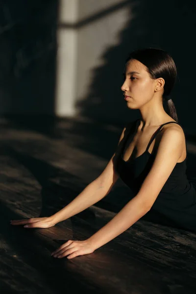 Fata îşi aruncă spatele întins pe stomac. Clasa de yoga în haine negre . — Fotografie, imagine de stoc