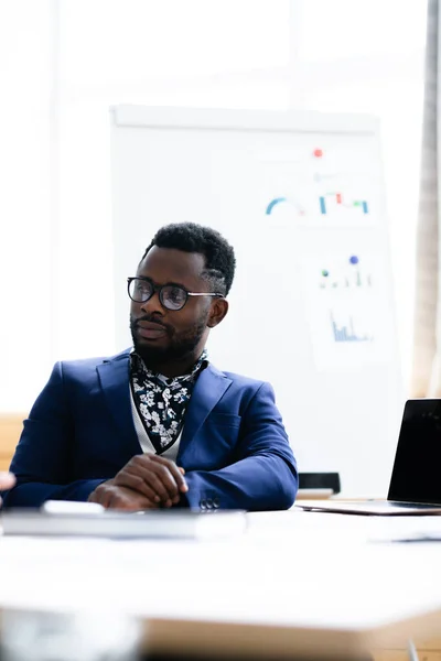 El empresario africano escucha atentamente el informe de uno de sus subordinados. En el fondo una pizarra blanca con un fondo borroso — Foto de Stock