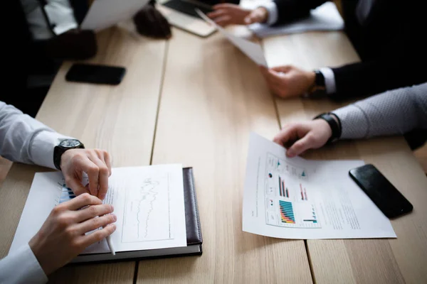 Hands of four businessmen of different nationalities with charts of company subsidiaries — Stockfoto