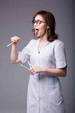 Genç kadın doktor, hastaya muayene aletlerini kullanarak dilini nasıl çıkaracağını göstermek için dilini dışarı çıkardı.
