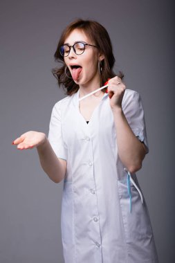 Genç kadın doktor, hastaya muayene aletlerini kullanarak dilini nasıl çıkaracağını göstermek için dilini dışarı çıkardı.