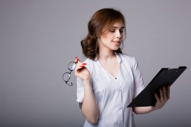 Avrupalı bir doktor nazikçe gülümser ve hastalarının listesini içeren siyah bir tablet tutar ve hasta hastalıklarının ana belirtilerini yazar.