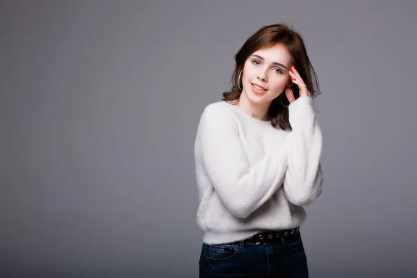Menina espanhola jovem em um suéter leve jovialmente colocar a mão atrás de sua cabeça e olha para a câmera alegremente — Fotografia de Stock