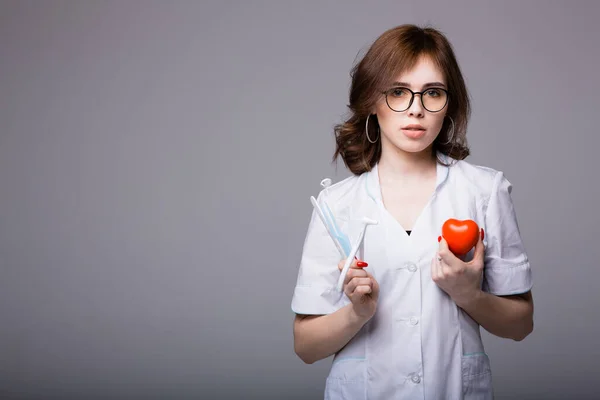 Young woman doctor stands with tools for examining a patient urging not to postpone a visit to the doctor in order to maintain health — Stock Photo, Image