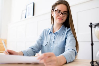 Gözlüklü ve gömlekli yakışıklı yönetici parlak bir ofiste başarılı satışların istatistiklerini inceliyor.