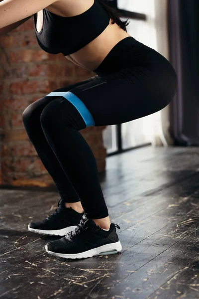 Kalçasında mavi bir lastik bantla mekik çeken kız sporcu. Kalçaların kasları için egzersiz.. — Stok fotoğraf