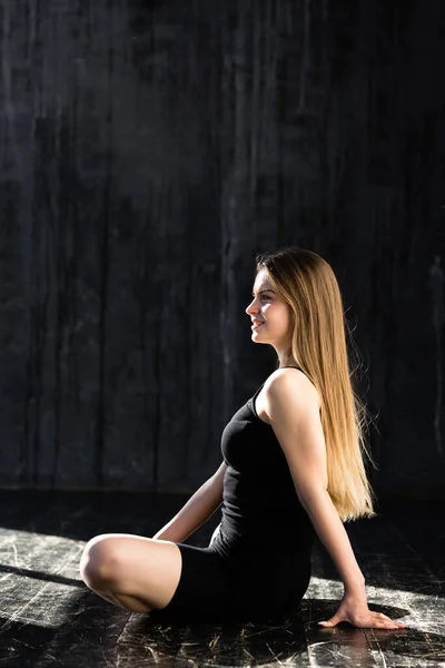 Гарна дівчина з довгим волоссям у чорному спортивному лаві займається ранковою йогою і сидить у позі Лотоса.. — стокове фото