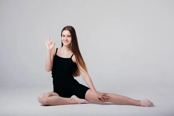 Una giovane ragazza in abbigliamento sportivo nero fa yoga e mostra un segno ok perché lo yoga non è complicato — Foto Stock