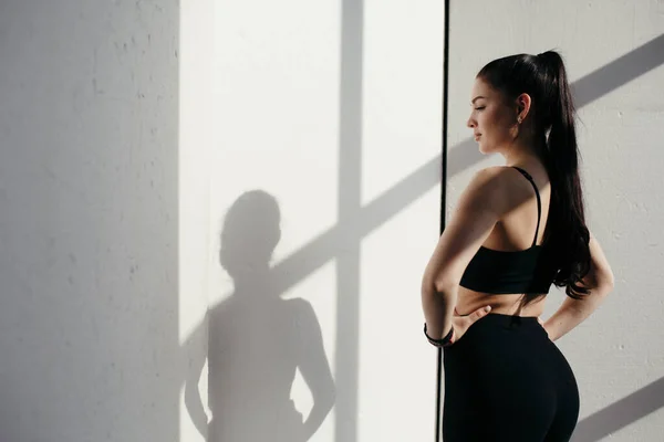 Attraente ragazza in piedi dietro la fotocamera. Ha gonfiato l'addestratore del prete nei jodhpurs neri. Fondo bianco . — Foto Stock