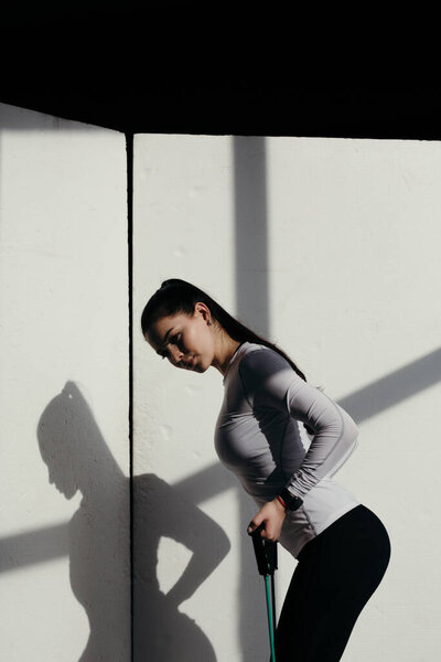 Attractive trainer do fitness at home at the time of isolation. Exercises with an expander