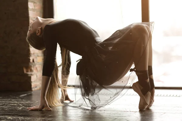Bailarina menina flexível está em suas mãos e pés e bela caverna nas costas. Menina em saia preta e sapatos Pointe . — Fotografia de Stock