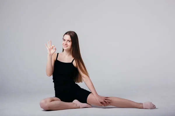 Une jeune fille en vêtements de sport noirs fait du yoga et montre un signe ok parce que le yoga n'est pas compliqué — Photo