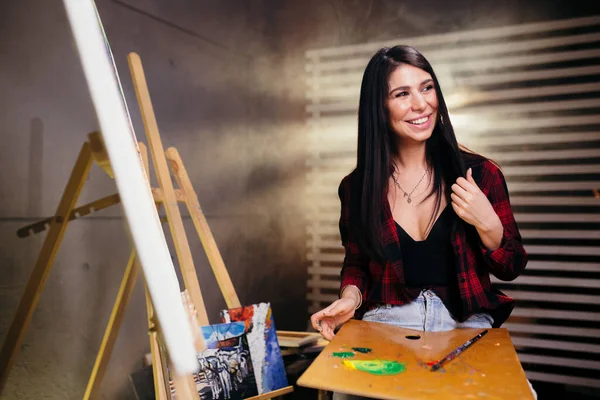 Het meisje tekent prachtige aquarel abstracte schilderij op doek met een borstel in een met rook gevulde kunst Studio. — Stockfoto