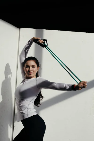 検疫中に運動する運動女子。コーチはエクスパンダを使って背中を伸ばし. — ストック写真