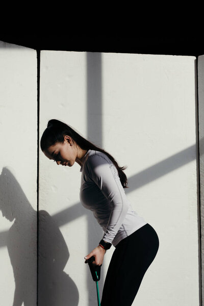 Attractive trainer do fitness at home at the time of isolation. Exercises with an expander.