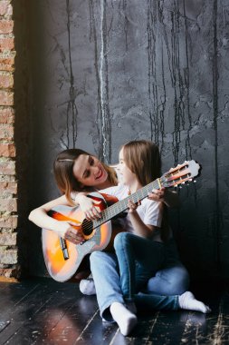 Genç bir anne kızına klasik gitar çalmayı öğretiyor. Ebeveynler ve çocuklarla ailecek vakit geçirmek