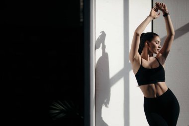 Siyah spor giysili atletik kız güneşin altında dikiliyor. Eğitim sırasında doğal ışık