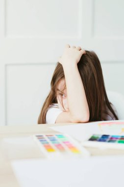 Küçük kız çizmekten yoruldu ve dinlenmek için uzandı. Kız yaramaz ve çizmek istemiyor..