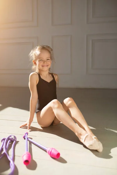 Belle jeune gymnaste fait des exercices avec des tiges roses gymnastique. Exercice et étirement des enfants . — Photo