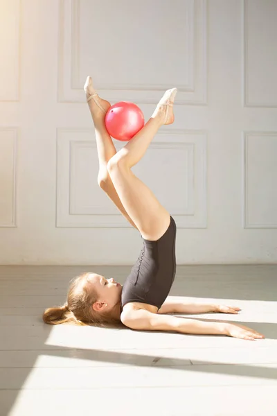 Exercices avec balle de gymnastique. Petite fille effectue des tours de gymnastique avec balle sur fond blanc — Photo