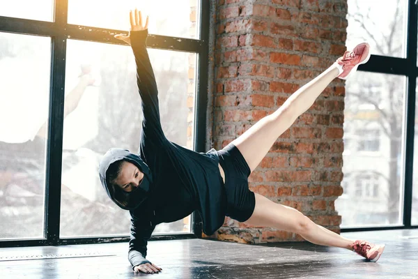 Pilates selama isolasi dan karantina. Gadis sporty bertopeng hitam dan tunik melakukan latihan untuk memompa otot. — Stok Foto
