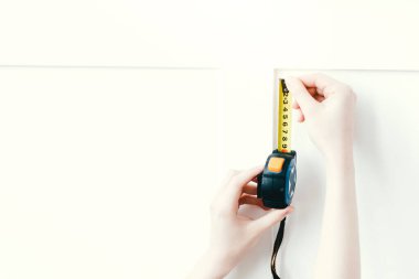 Dairenin içindeki panelleri ölçmek için sarı şerit mezura kullanan kadın eller..