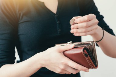 Siyah ceketli kadın deri çantasından bozuk para çıkarıyor. Satın almak için nakit.