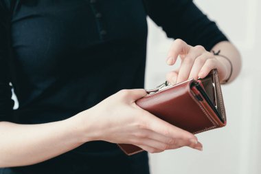 Kadın eli parayı deri bir çantaya koydu. Ödemeden sonra teslimat. Beyaz arkaplan.