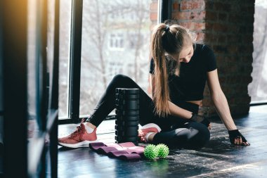 Evde uzun saçlı kız sporla meşgul. Spor için uygun. Masaj silindiri, top miyofasyal ve spor için pembe kurdeleler..