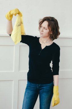 Onaylamayan genç kız pis sarı paçavraya bakıyor. Tamir sonrası temizlik. Kadın tozları siliyor..