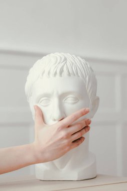 Kadın eli oyulmuş kafaya kapalı ağız. Enfeksiyon ve koronavirüse karşı koruma kavramı. Sezar 'ın kafası.