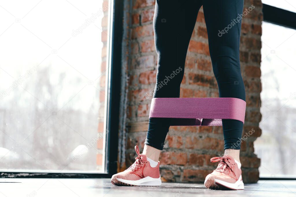Close-up. Beautiful slender legs in black leggings with pink sports tape for ankles.