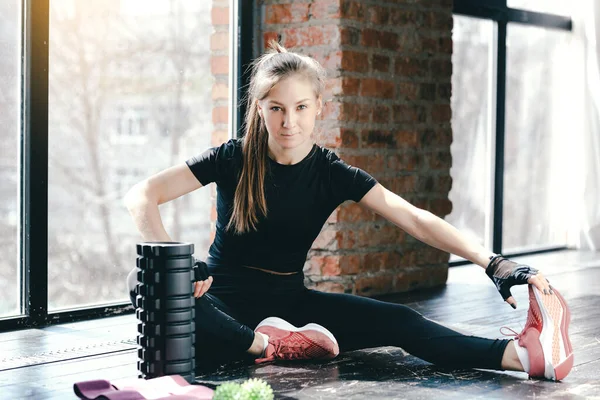 Ung flicka vilar efter träning med massage roller och intensiv träning med bollen myofascial och övningar med rosa band — Stockfoto