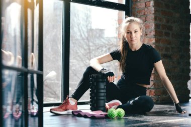 Karantina sırasında yatay fotoğraf sporu. Koç pilates yapıyor. Masaj silindiri, top miyofasyal ve spor için pembe kurdeleler.