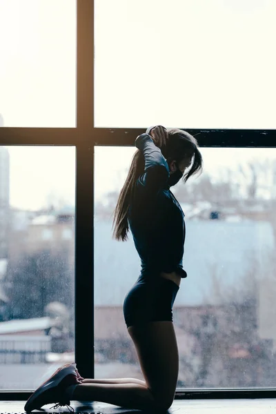 예쁘고 날씬 한 몸매의 적합 한 소녀. 요가 조련사 창문을 치는 작업중에 꼬리를 감는다. — 스톡 사진