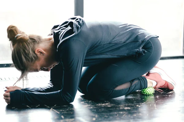Fêmea de close-up em leggings pretos. Exercício dos músculos com uma bola miofascial verde . — Fotografia de Stock