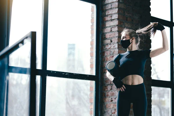 Schöne schlanke Profil eines fitten Mädchens. Yogatrainer mit schwarzem Massageroller bindet Schwanz beim Training gegen ein Fenster. — Stockfoto