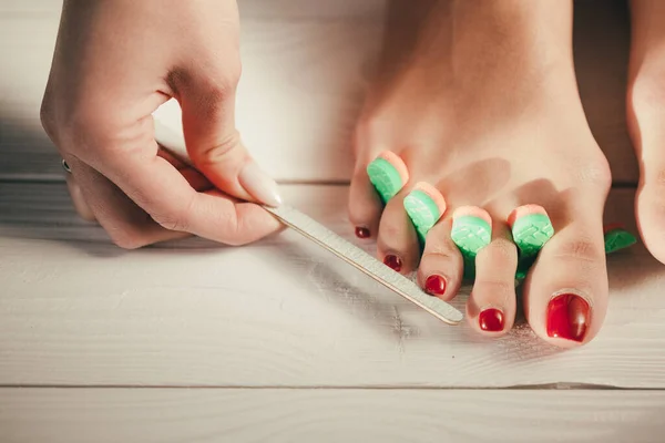 Pedicure in a professional beauty salon. Toe separators during nail files. Advertising photo for manicure salon