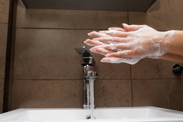 少女は、自己分離中のコロナウイルス感染の脅威から保護するために抗菌石鹸でシンクの手で洗浄します。 — ストック写真