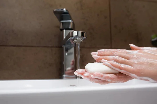 Mytí rukou v bílém dřezu. Voda teče do mýdlových ženských rukou. Ochrana proti koronaviru a infekcím. — Stock fotografie