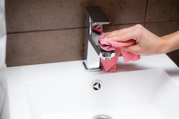 Bir kız krom musluğu mikrofiber bezle parlatıyor. Ev ve banyo temizliği. — Stok fotoğraf
