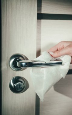 Kadın eli bir bezle kapı kolunu siler. Koronavirüs salgını sırasında yüzey dezenfeksiyonu