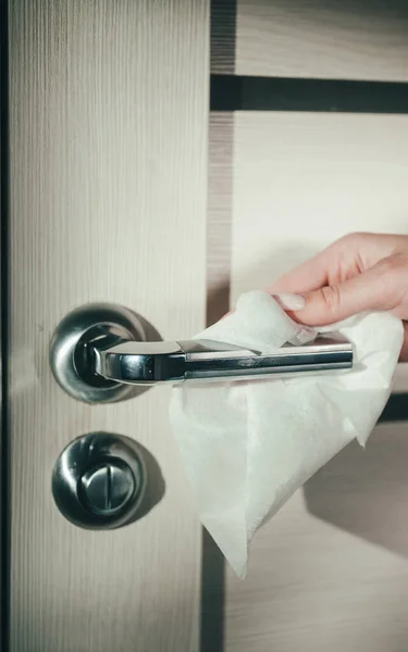 布で女性の手とドアハンドルを拭く。コロナウイルス流行時の表面消毒 — ストック写真