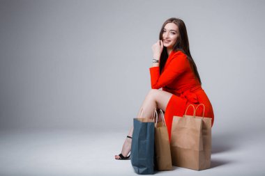 Güzel bir kadın bir sandalyede oturuyor ve satın aldıklarının yanında. Alışveriş merkezinde satışlar ve mutlu bir alıcı..