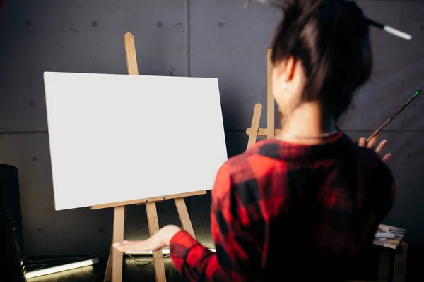 Blank Mock Up Canvas. Artist is in Studio in front of the easel and looks at the new abstract watercolor color painting.